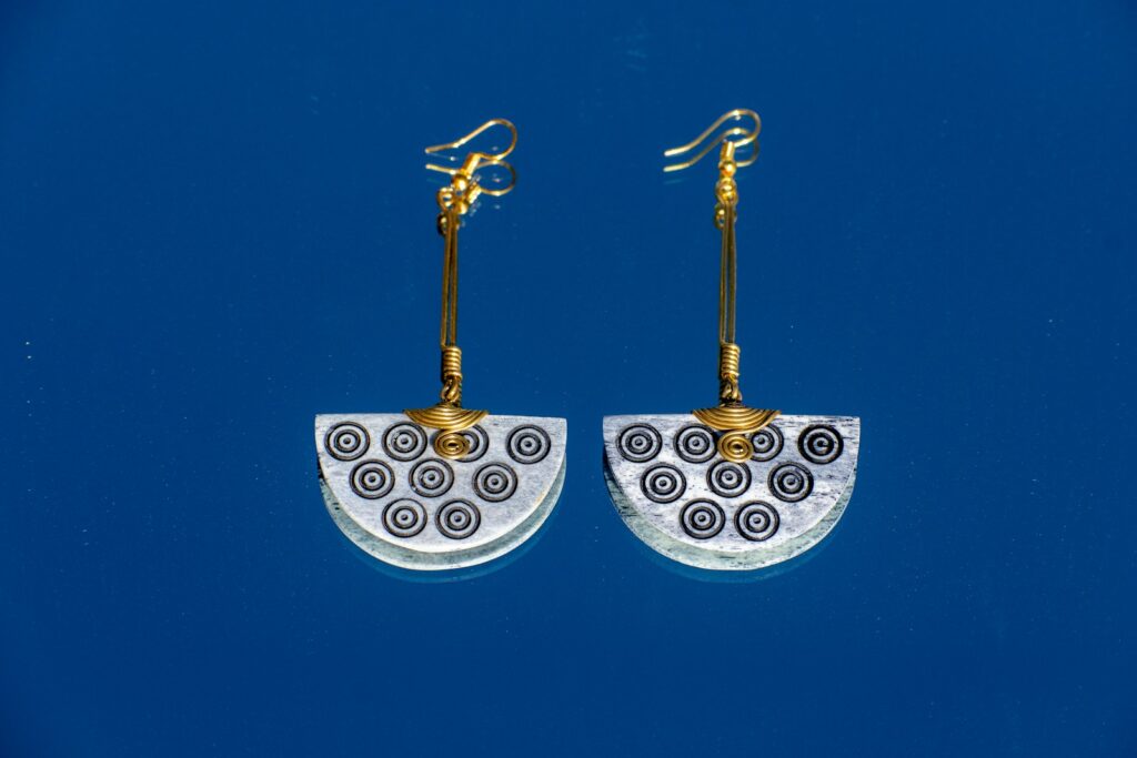 A pair of white and gold earrings on a blue background